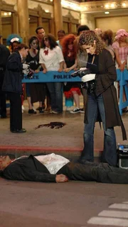 Detective Stella Bonasera (Melina Kanakaredes) fotografiert die Leiche eines Mannes (Jeff Brockton), der auf der Straße tot zusammengebrochen ist.
