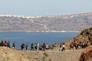 Von der zentralen Vulkaninsel Nea Kameni aus sind der steile Kraterrand von Santorin und die Kulisse der Stadt Fira besonders eindrucksvoll.