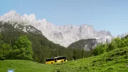 Das Postauto vor beeindruckender Bergkulisse.