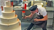 Bevor die Hochzeitstorte "New English Classic" dekoriert wird, sprüht Konditormeister Christian Böckeler eine Hälfte mit dunkler Kuvertüre ein.