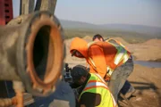 Parker in orange hoodie helping fix a rock truck.