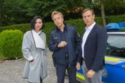 Polizist Mohr (Max Müller, M.) und Kommissar Bach (Patrick Kalupa, r.) ermitteln, nachdem ein Pooldesigner im Garten von Theresa Strasser (Mimi Fiedler, l.) ermordet aufgefunden wurde.