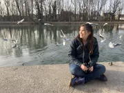 Anna sitzt an der Isar und beobachtet Lachmöwen mit dem Fernglas.
