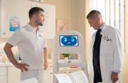 Dr. Kaminski (Udo Schenk, re.) ist skeptisch über den "neuen Kollegen", von dem Kris Haas (Jascha Rust, li.) natürlich seine Finger nicht lassen konnte und ihn selbst programmiert hat.
