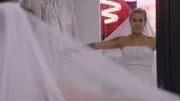 Ximena fans out a veil while trying on a wedding dress.