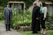 Inspector Mallory (Jack Deam, l.) verkündet, dass Mrs. Rudge aufgrund eines verstopften Kamins durch die Rauchentwicklung starb. Father Brown (Mark Williams, M.) und Bunty (Emer Kenny, r.) haben jedoch ihre Zweifel daran, dass es sich um einen Unfall handelt.