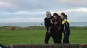 Mit der Unterstützung von Sarah Kelly (Róisín O’Donovan, re.) bringt Superintendent Sean Kelly (Declan Conlon, li.) seinen benommenen Neffen Eoin (Levi O’Sullivan, Mitte) zum Auto.