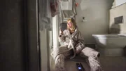 Anita sits on the bathroom floor with a gun in her hand.