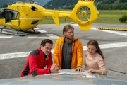 Tobias (Markus Brandl, l.), Markus (Sebastian Ströbel, M.) und Lara Fellner (Leonie Rainer, r.) besprechen am Heliport die weitere Vorgehensweise.