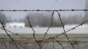Zaun mit Sicht auf Baracke.