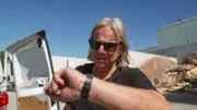 Jörg Hartmann stands with sunglasses in the yard of the recycling company, looks at the clock