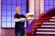 Rateteam-Kapitän Bernhard Hoëcker bringt den "Burger" für den ehemaligen Fußballspieler und -Trainer Holger Stanislawski.