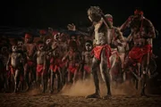 Aborigine-Männer und eine Gruppe von Aborigine-Kindern beim Tanzen. -- Fotoreportage über das Derby Aboriginal Corroboree, das größte traditionelle Corroboree, das für die Öffentlichkeit in Westaustralien zugänglich ist und ein authentisches Erlebnis der Kultur der Kimberley Aborigines bietet.