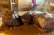 Für ein saftiges Hirschsteak wird Fleisch angebraten, ein Fond aus Zwiebeln, Karotten und Hirschknochen gekocht und anschließend über das Steak gegeben.