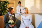 Das Ärzteteam wird von einem plötzlichen Ansturm auf die Praxis überrascht: Mehrere Patienten klagen über heftigen Husten und Übelkeit, doch seltsamerweise zeigt keiner von ihnen die üblichen Fiebersymptome. Lisa (Marie Seiser, M.) versorgt Jessica Biehler (Caroline Maria Frier, r.) und Norbert Kerner (Hendrik von Bültzingslöwen, l.).