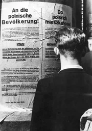 Ein Mann liest ein NS-Plakat über Pflicht-Arbeiten für polnische Bürger.