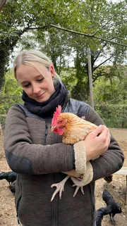 Shanna wird bei der Arbeit im Hühnergehege von kleinen Helfern unterstützt.
