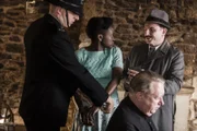 Inspector Mallory (Jack Deam, r.) lässt die junge Grace Kemp (Pepter Lunkuse, 2.v.l.) für den Mord an ihrem Vater verhaften. Father Brown (Mark Williams, 2.v.r.) glaubt jedoch an Graces Unschuld und will ihr helfen, diese zu beweisen.
