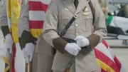 Ein Offizier steht vor der amerikanischen Flagge, während sie einem gefallenen Offizier in Mayaguez, P.R., gedenken.