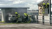Firefighters extinguish a burning car.