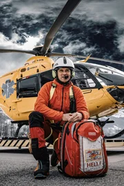 Ulli Steiner mit Helm und Notarzt-Rucksack vor dem Rettungshubschrauber am Heliport.
