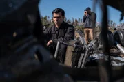 The Main Investigator (played by RJ Parrish) surveys the crash site of US-Bangla Airlines Flight 211, while another investigator documents the wreckage.