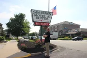 Host Anthony Melchiorri strikes a pose in front of the sign for the Simmons Motel in Hershey, Pennsylvania, as seen on Travel Channel's Hotel Impossible.