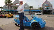 Host Anthony Melchiorri poses in front of a three-wheeled vehicle which he drove to the Lancer Motel.