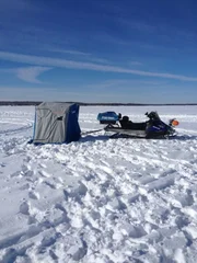 Snowmobile and portable tent on an empty lake.