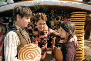 Die Hexe (Anja Kling, Mitte) lädt Hänsel (Friedrich Heine) und Gretel (Mila Böhning) zu sich ins Knusperhäuschen ein.