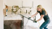 Jasmine Roth takes a sledgehammer to the cabinets in the kitchen during demolition.
