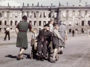 Familie vor einer Ruine, die einen Holzkarren schiebt.