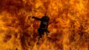 Ein Samurai-Krieger springt im Kampf heldenhaft durch die Flammen.