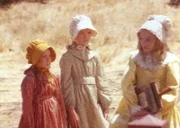Nellie Oleson (Alison Arngrim, r.) straft Mary (Melissa Sue Anderson, M.) und Laura (Melissa Gilbert, l.) mit verächtlichen Blicken.