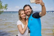 Julian Trautmann (Patrick G. Boll, r.) und Christin Lange (Sarah Thonig, l.) stehen am Ufer des Grundstücks, auf dem Julian seinen mobilen Surfbrettverleih eröffnen will, und genießen den unbeschwerten Augenblick.