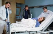 Daniel (Ben Blaskovic, mi.) will Tina (Heike Warmuth, liegend) erklären, warum er sie angelogen hat. Doch Tina bekommt plötzlich starke Schmerzen und Dr. Martin Stein (Bernhard Bettermann, li.) und Kris Haas (Jascha Rust, re.) müssen sie sofort in den OP bringen.