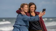 Ein schöner Tag am Strand. Beim Spaziergang am Meer haben Mette (Valerie Niehaus, l.) und Ina (Julia Brendler, r.) eine gute Zeit. Ein Selfie der beiden soll den Moment festhalten.
