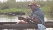 Cody Lundin sits in canoe with manmade paddle.
