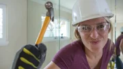 As seen on Hidden Potential, designer Jasmine Roth playfully holds a small hammer before removing a large living room wall mirror during demo at the Yapelli residence in Huntington Beach, CA.