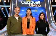 Moderatorin Esther Sedlaczek (M.) mit den Kandidat:innen des Teams "Kamera": Dem Schauspieler Jörg Hartmann (l.) und der Schauspielerin Aylin Tezel (r.).