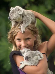 Izzie holding two koalas smiling at the camera.
