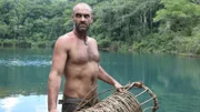 Ed Stafford holding a fashioned fishing basket in both hands on a raft in the Lacandon sink hole in Guatemala.