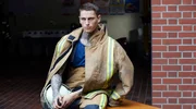 Die Feuerwehr Hasselhude lernt das Öffnen von Türen im Brandeinsatz: Feuerwehrmann Olli (Fabien Tietjen) beobachtet das Training.