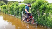 Land unter in der Kleingartenanlage. Daniel kommt auf dem Fahrrad schwer voran..