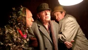 Brakelmann (Jan Fedder, Mitte) hat sich beim Wildern angeschossen. Kuno (Sven Walser, li.) und Adsche (Peter Heinrich Brix, re.) bringen ihn ins Haus.