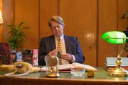 Ein Mann sitzt an einem Tisch und hält ein Spielzeug