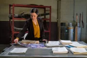 REENACTMENT - The Second Investigator (played by Jenny Young) analyzes the crash site photos of UPS Flight 1354 to try to piece together what caused the aircraft to crash.