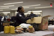 Officer Arrisia Sima inspects a passenger's package filled with food products. (National Geographic/Lucky 8 TV)