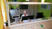 Campingplatzmitarbeiterin Anne jessen hinter der neuen Sicherheitsscheibe.