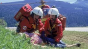Florian Lenz (Jo Weil) und Dr. Karin Thaler (Roswitha Meyer) haben die verletzte Sonja (Nora Heschl, lieg.) geborgen.